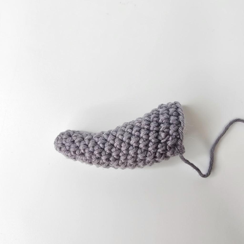 Crocheted elephant trunk in grey cotton worsted weight yarn that curves upwards. This is part of a free crochet elephant lovey pattern designed by Cilla Crochets.